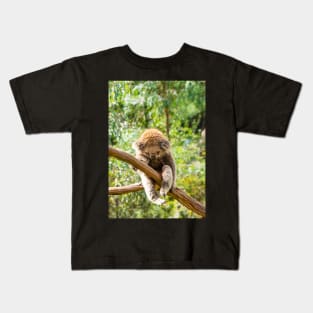 Koala with leg hooked over gum branch. Kids T-Shirt